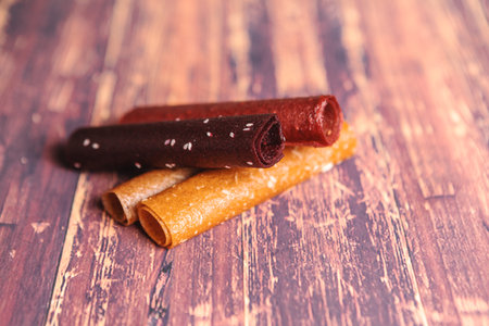 fruit pastilles are rolled into tubes and stacked on top of each other on a wooden background