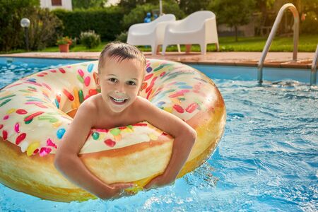5 years old Boy in swimming pool on inflatable colorful ringの写真素材