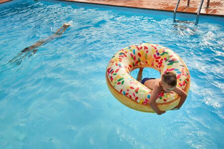 5 years old Boy in swimming pool on inflatable colorful ring