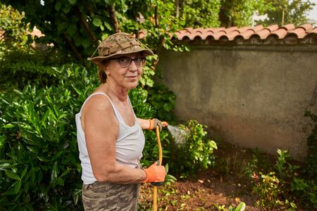 Senior woman in retirement working in the garden loking in cameraの写真素材