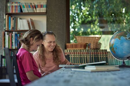 Mother and daughter infront of the laptop studying online