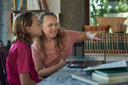 Mother and daughter infront of the laptop studying onlineの写真素材