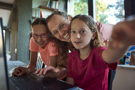 Mother helping for two girls infront of the laptopの写真素材