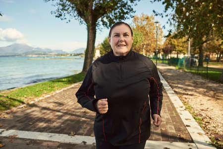 Active senior woman doing healthy exercises outdoors. Joggingの写真素材