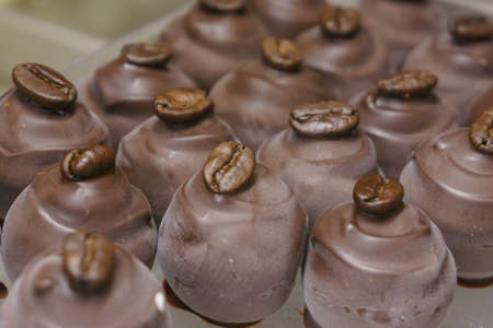 Patern of many coffee bean toped dark chocolate pralines