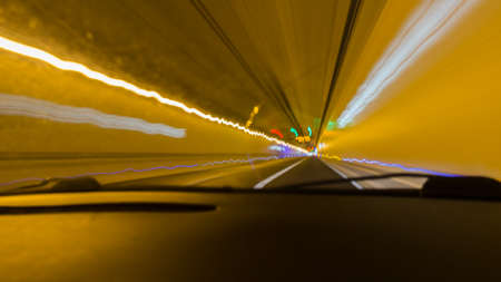 looking out of a windshield while driving through tunnel with blurry lights