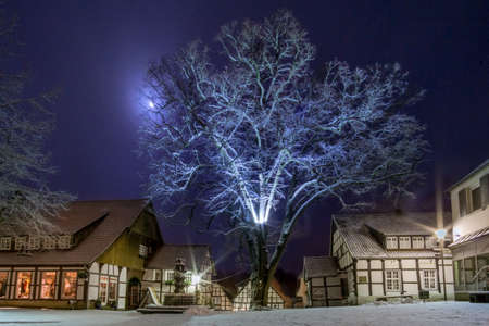 romantic nightscape at old German city with half-timbered houses and snow covered tree in moonlight, Tecklenburg, Germanyの写真素材