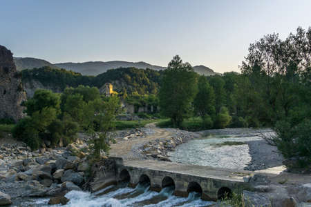 Mountain landscape at sunset with path over river to get to abandoned village of Janovas with golden...