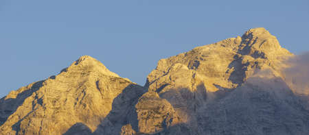 golden color of mountain peaks at sunrise in triglav national park, sloveniaの写真素材