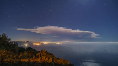 Etna volcano after eruption with smoke and big cloud in front of the mediterranean sea at night with stars on February 10 2022 , Sicily, Italyの写真素材