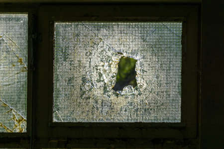 Detail of broken window looking outside of an empty industrial building