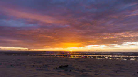 Beautiful sunset with dramatic moody cloudy sky above the ocean of North Sea, De Haan, Belgium.の写真素材