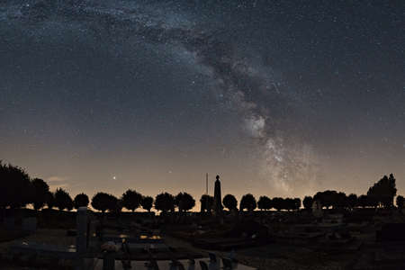 Milky Way over french cemetery with silhouette of trees at night, Normandy, France