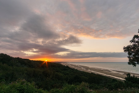 View over Omaha beach on the french atlantic coast during sunset with red sunlight touching the clouds, Colleville-sur-Mer, Normandy, Franceの写真素材