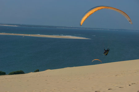 Single paraglider flying in the windy air over the dune of Pilat on a sunny day, Arcachon, Nouvelle-Aquitaine, Franceの写真素材