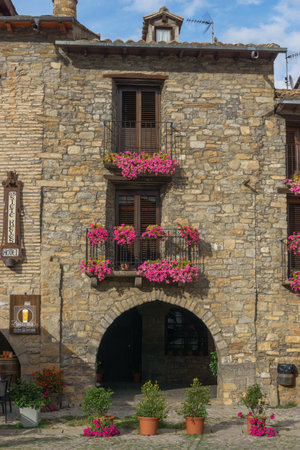 Old stone house with beautiful flowers at the window in the medieval village of Ainsa in the pyrenees, Aragon, Spainの写真素材