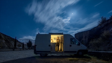 Camper van with opened door in the moonlight at night