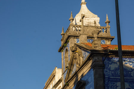 Tower of Chapel of Souls or Capela das Almas with beautiful blue white azulejo tiles facade illuminated by golden sunlight in Porto, Portugalの写真素材