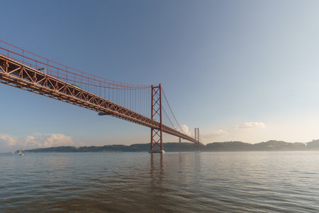 Red bridge 25 de Abril Bridge and statue of Cristo Rei during a slightly misty day, Lisbon, Portugalの写真素材