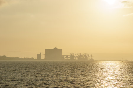 Terminal Portuario da Trafaria the port of Trafaria with cranes in the hazy distance during golden...