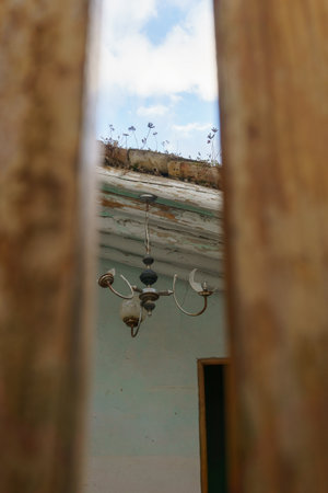 An old ceiling light in an abandoned building seen through wooden door