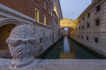 Small canal passing towards illuminated famous Bridge of Sighs or Ponte dei Sospiri during evening twilight, Venice, Veneto, Italyの写真素材