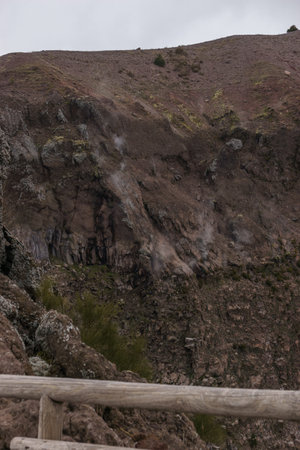 Landscape on top of the crater of dormant Vesuvius volcano with smoke rising out of the rocks,...