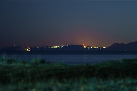 Crescent moon rising over illuminated coastal landscape at night, Paestum, Campania, Italyの写真素材