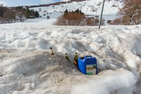 Empty glass bottles and plastic canisters in the snow left from ski tourists at Madonie Natural Park...