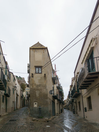 Narrow street in the old town of Cefalu on a cloudy rainy day, Sicily, Italyの写真素材