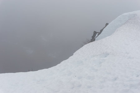 Snowy view of the mountain landscape of Vosges with edge of a cliff on a foggy winter day, Alsace,...
