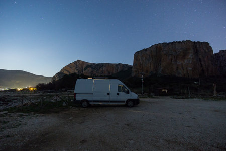 Van in front of rock formation at Nature Park of Monte Cofano during night time with stars on the sky, San Vito Lo Capo, Sicily, Italyの写真素材