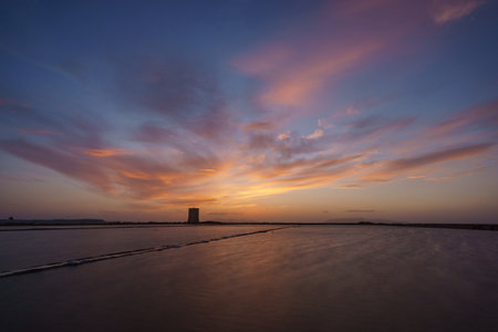 Vibrant sky during evening twilight after sunset at nature reserve Saline di Trapani with salt fields and Torre Nubia, Contrada Nubia, Sicily, Italyの写真素材