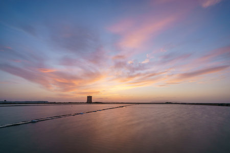Vibrant sky during evening twilight after sunset at nature reserve Saline di Trapani with salt fields and Torre Nubia, Contrada Nubia, Sicily, Italyの写真素材