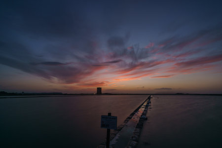 Vibrant sky during evening twilight after sunset at nature reserve Saline di Trapani with salt fields and Torre Nubia, Contrada Nubia, Sicily, Italyの写真素材
