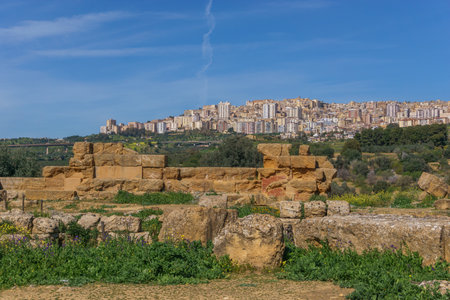 Modern city and ancient wall of a ruin at Valley of the Temples, Agrigento, Sicily, Italyの写真素材