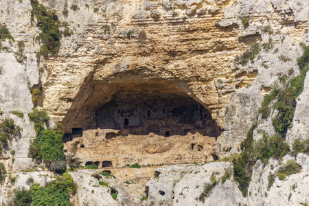 Prehistoric cave of necropolis carved in rock formation at canyon of Oriented Nature Reserve Cavagrande del Cassibile, Syracuse, Sicily, Italyの写真素材