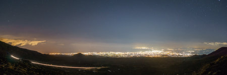 Panoramia of illuminated Catania from Etna at starry night with light trail on road through volcanic landscape, Catania, Sicily, Italyの写真素材