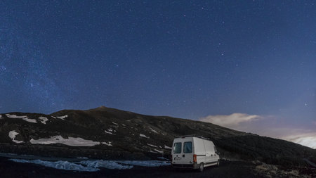 Camper Van under night sky with stars over volcanic landscape of Mount Etna during winter time, Catania, Sicily, Italyの写真素材