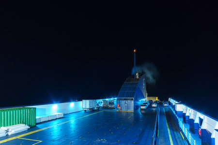 Cars on illuminated open deck at ferry boat during nighttime in the Adriatic sea, Italyの写真素材