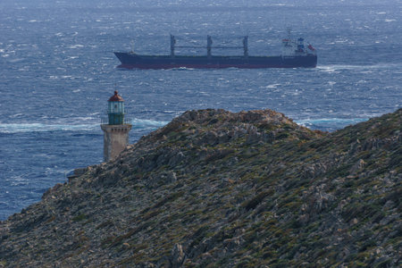 Rocky cape Tainaron with view at lighthouse and cargo ship swimming at the Mediterranean sea, Mani, Peloponnese, Greece.の写真素材