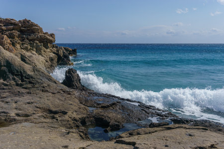 Sea water splashes at petrified tree at Geopark of Agios Nikolaos Petrified Forest at mediterranean sea coast, Laconia, Peloponnese, Greeceの写真素材
