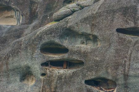 Detail view of eroded caves in side of sandstone rock formations of Meteora once inhabited by hermit monks, Kalambaka, Thessaly, Greeceの写真素材
