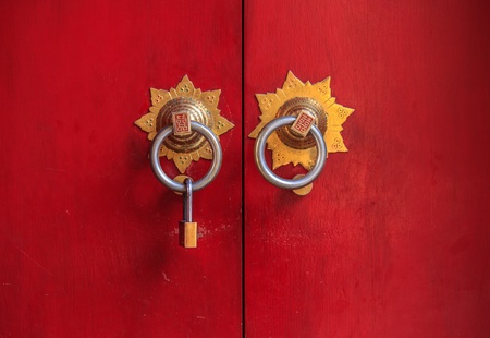 The Chinese style door made from wood painted with red color, with the modern u type lock hanging on knob due to required of secure の写真素材