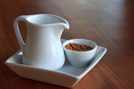 Milk and brown sugar in whiteware for coffee or tea break.の写真素材