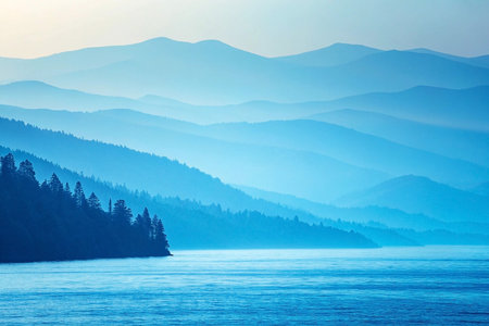 Serene blue mountain lake sunrise, misty layers, calm water, tranquil landscape, website bannerの素材