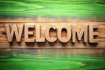 Wooden letters spelling welcome on a green wooden background. Possible use website banner, greeting cardの素材