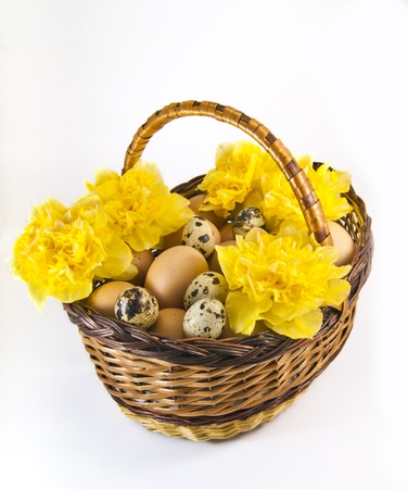 Chicken eggs in a basket with yellow flowersの写真素材