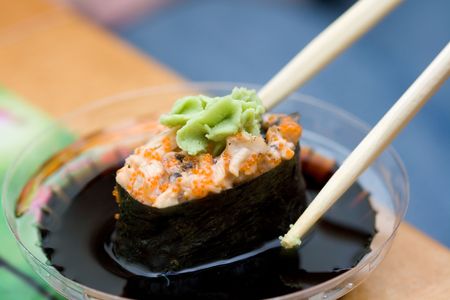 taking sushi with chicken and wasabi from plastic saucer with chopsticksの写真素材