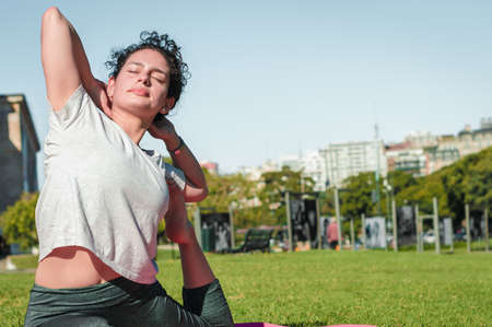 girl doing yoga pigeon pose in a park.